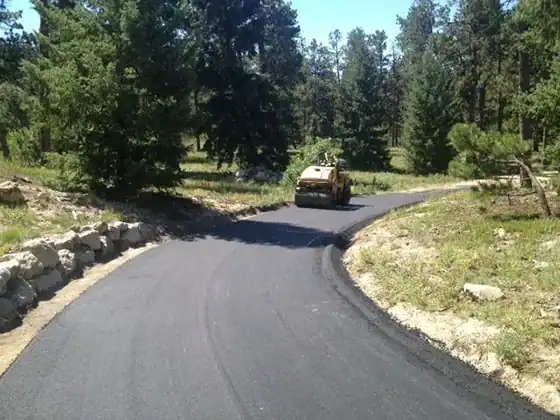 Roller compacting a new asphalt driveway winding through the pines in Black Forest, Colorado