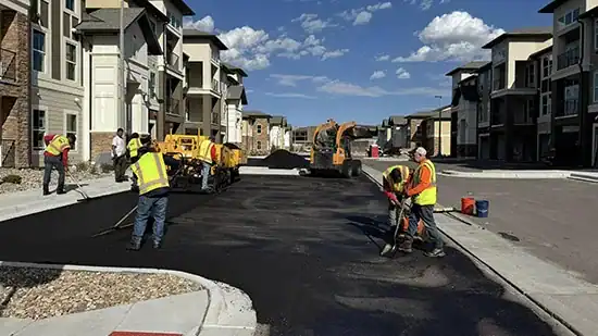 Paving crew raking and leveling hot-mix asphalt by hand during an asphalt repair in Colorado Springs