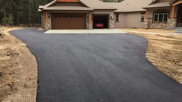 Freshly paved asphalt driveway curving up to a home with a two-car garage near Colorado Springs